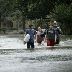 People evacuate a neighborhood inundated by floodwaters from Tropical Storm Harvey on Monday, Aug. 28, 2017, in Houston, Texas. (AP Photo/Charlie Riedel)