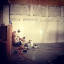 A worker begins to install some of 200 square feet of subway tile in the kitchen. (photo courtesy Mei Mei)