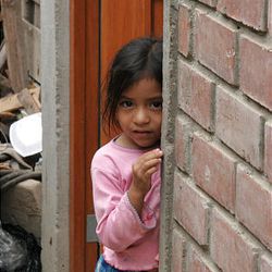 Maria Isabel Quispo, 5, peeks outside the doorway of her new home in Pisco, Peru, built by LDS Church.