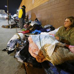 April Gifford sits on and in a pile of blankets outside the winter overflow shelter at St. Vincent de Paul in Salt Lake City as it opens just ahead of a winter storm Wednesday, Nov. 16, 2016.