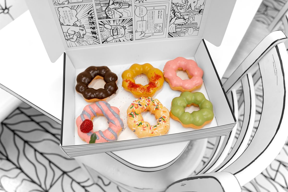 A black and white box holds six colorful pon de ring doughnuts.