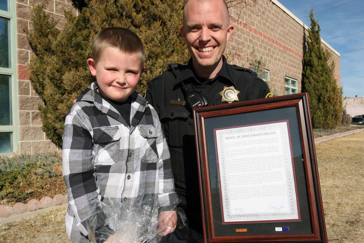 Carbon County sheriff's deputy Shawn Addley, right, was presented with a meritorious service award Thursday by Sheriff Jeff Wood for saving the life of 5-year-old Hayden Holt, left, and Holt's father, Jonathan from carbon monoxide poisoning on Dec. 12, 20