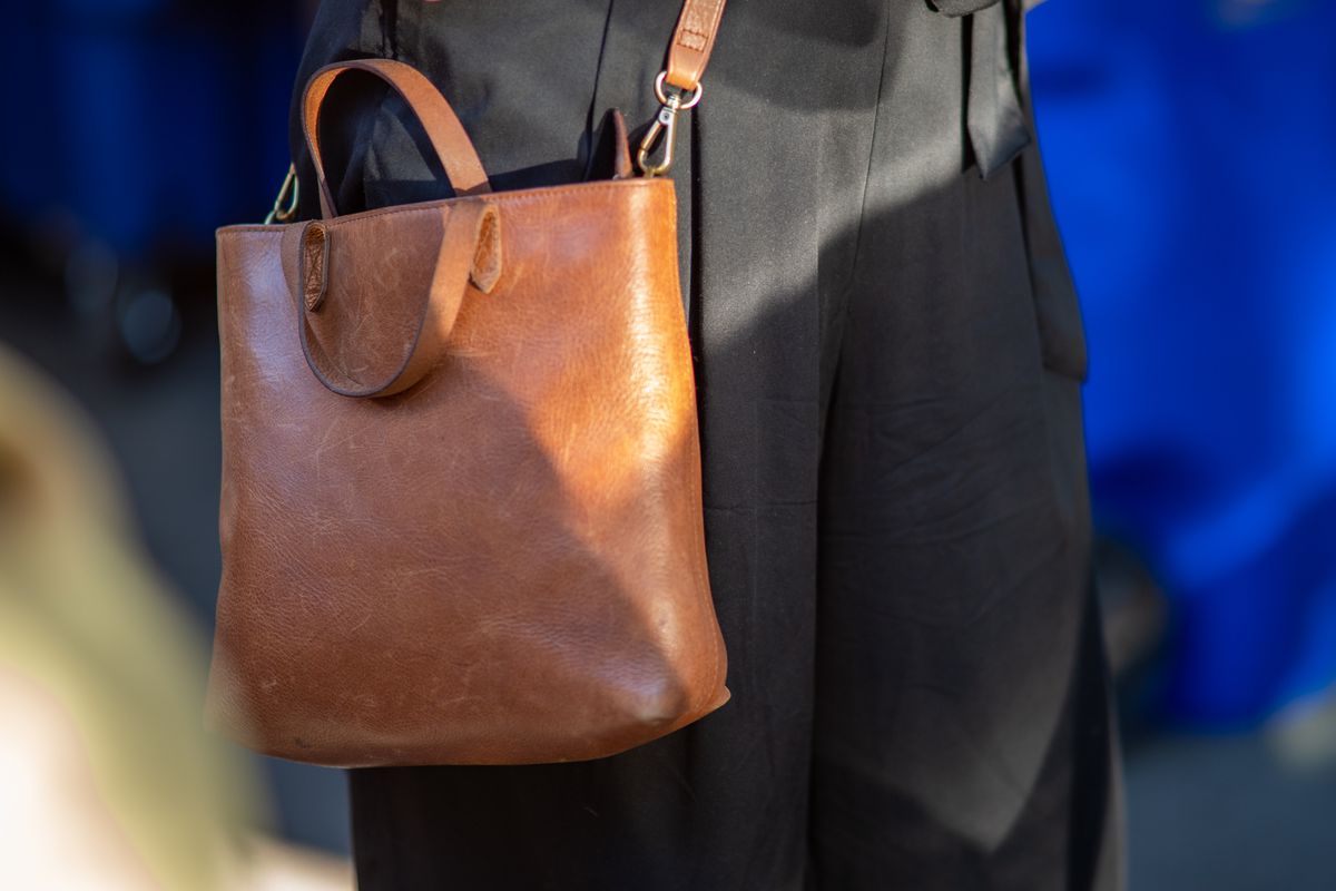 A person wears a brown leather bag