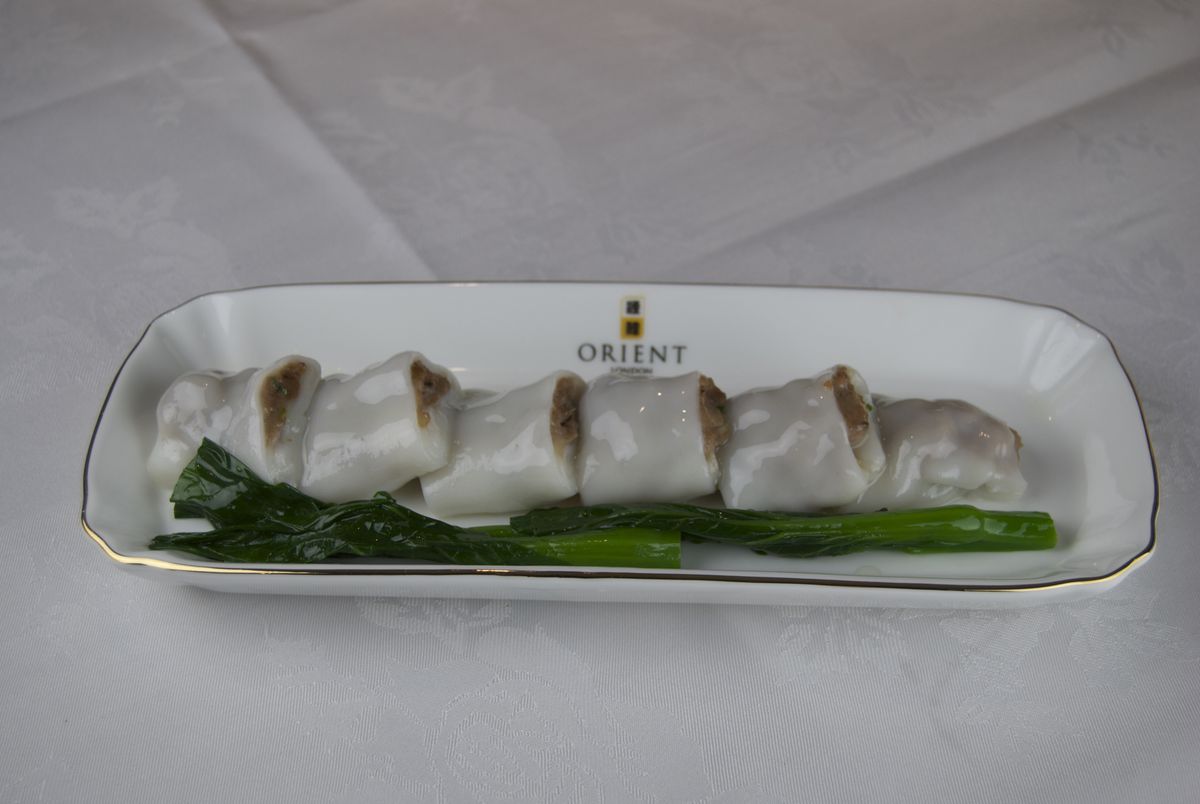 Find London’s best Chinese dumplings at Orient, like these cheung fun, served on a white plate with spears of gai lan.
