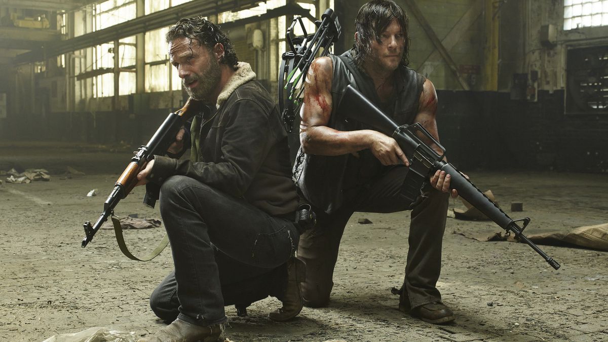 Two Walking Dead characters kneel while holding guns