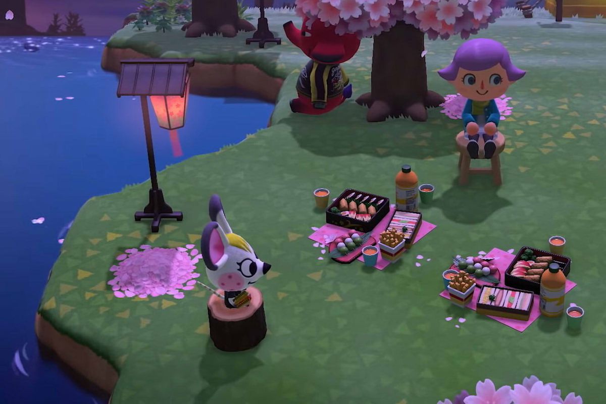 Animals sit around a villager under cherry blossoms at night in Animal Crossing: New Horizons for Nintendo Switch.