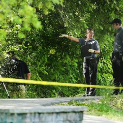 Salt Lake City police officers investigate a dead body found Monday, June 1, 2015, along the Jordan River Parkway Trail near 804 N. Riverside Drive.