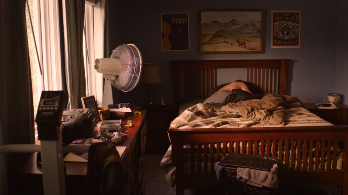 A shirtless man sleeping in his bedroom.