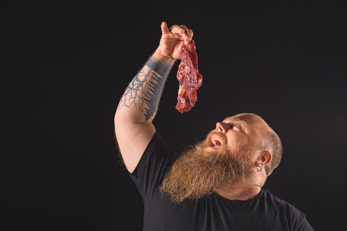 man eating raw beef stock photo