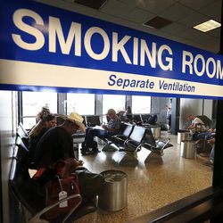 Travelers use a smoking room at Salt Lake City International Airport, Monday, Aug. 3, 2015.
