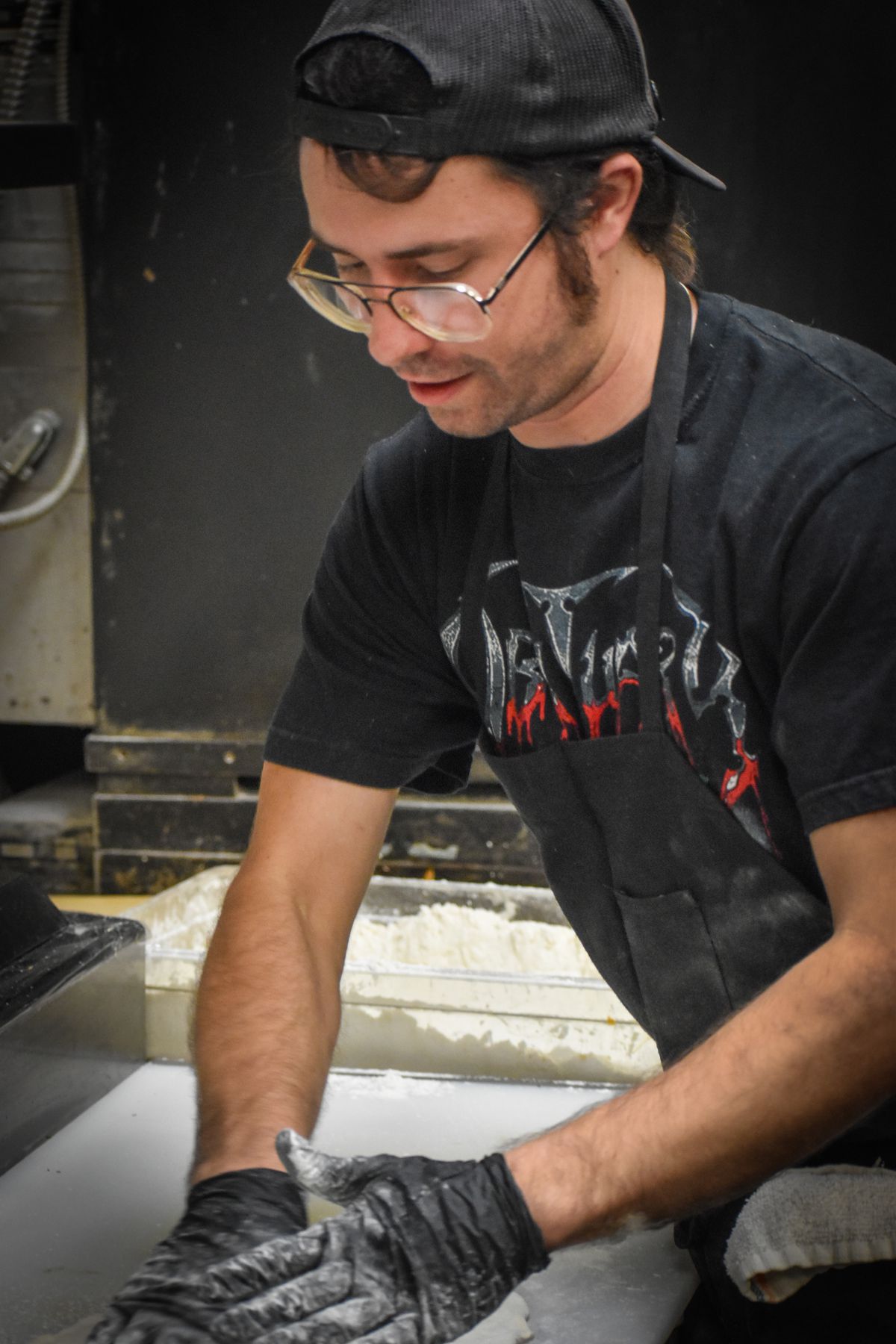 A chef in a black hat and black t-shirt makes pizza at 4th Horsemen.