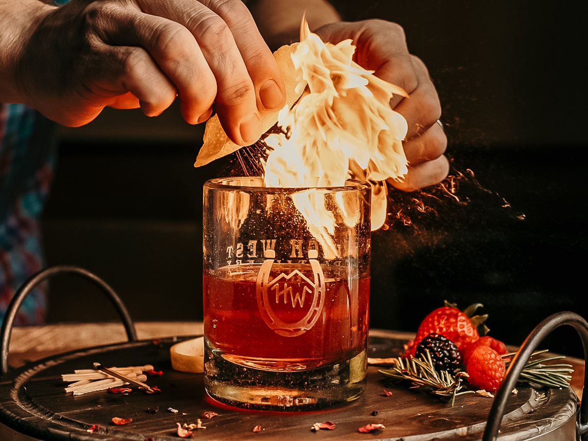 A bartender creates a ball of flame over a cocktail.