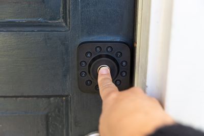 A finger touching a fingerprint reader on a door lock