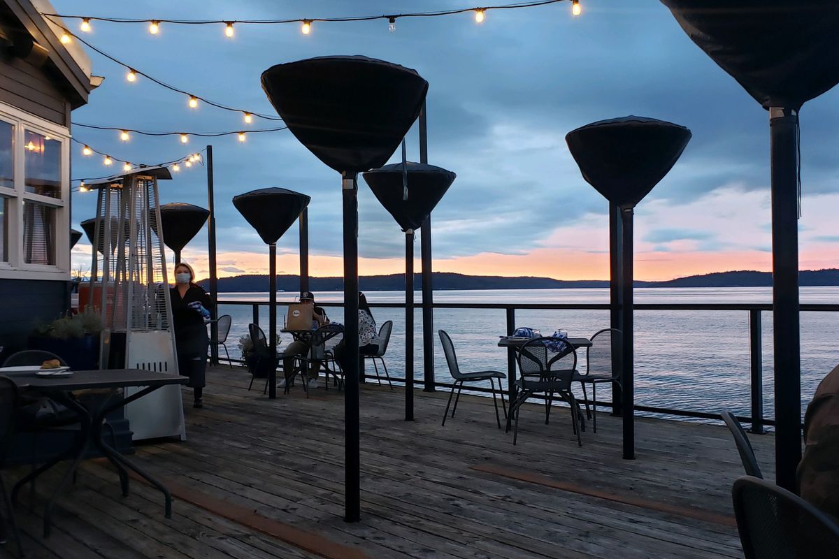 A view of the sound from Duke’s Chowder House in West Seattle, with a masked server and tables on the patio