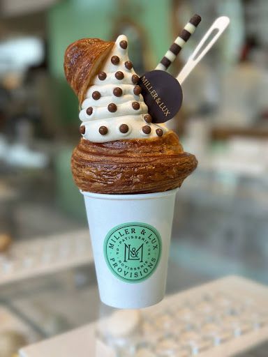 A croissant with one end sliced off and filled with ice cream, held inside a paper cup, from Miller &amp; Lux Provisions.