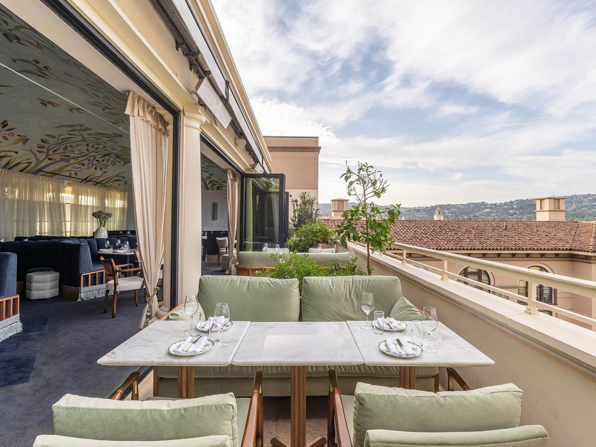 Plush green chairs and marble tables on a patio overlooking Beverly Hills at Dante.