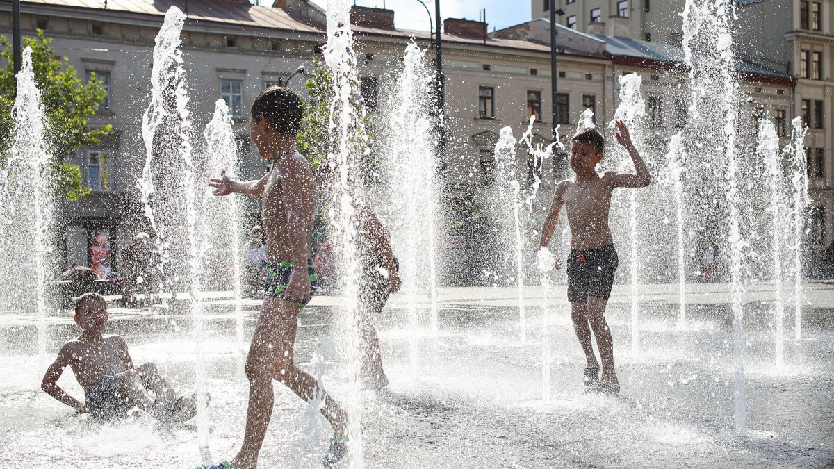 Children are cooling off in a water fountain near the Lviv...