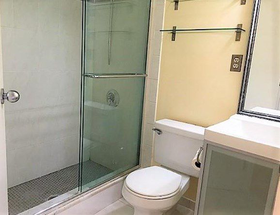 A small bathroom with a sliding glass door on the shower.