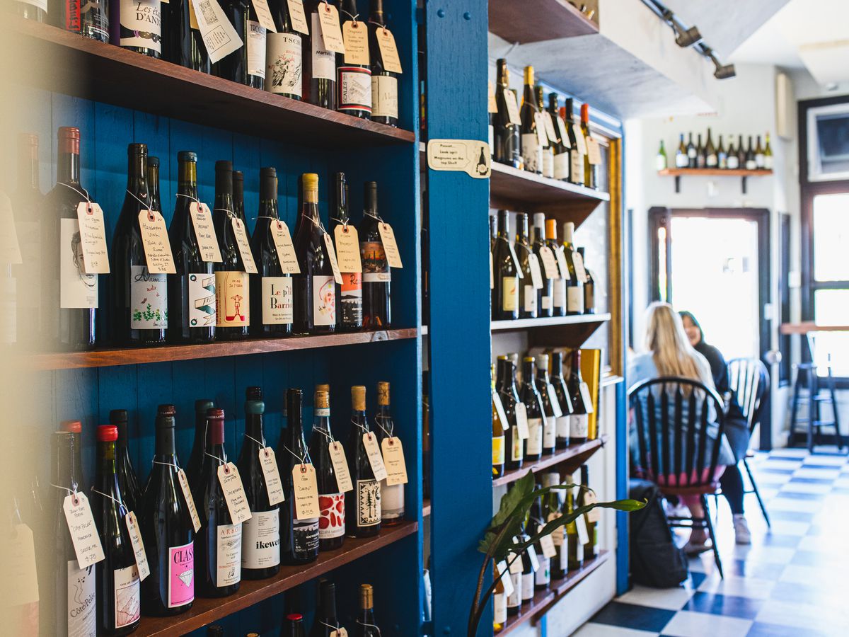 Wine bottles line several shelves inside Snail Bar in Oakland.
