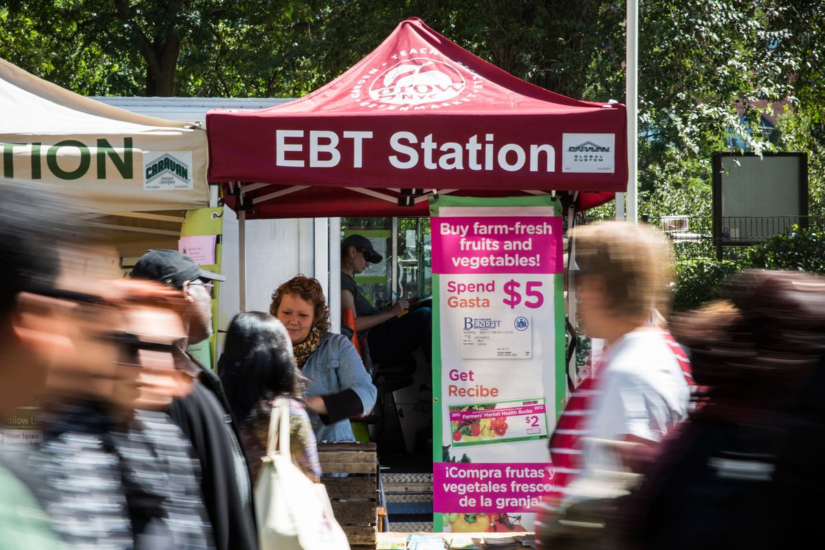 People walk past an EBT station, more commonly known as food stamps, in the GrowNYC Greenmarket in Union Square on September 18, 2013, in New York City.