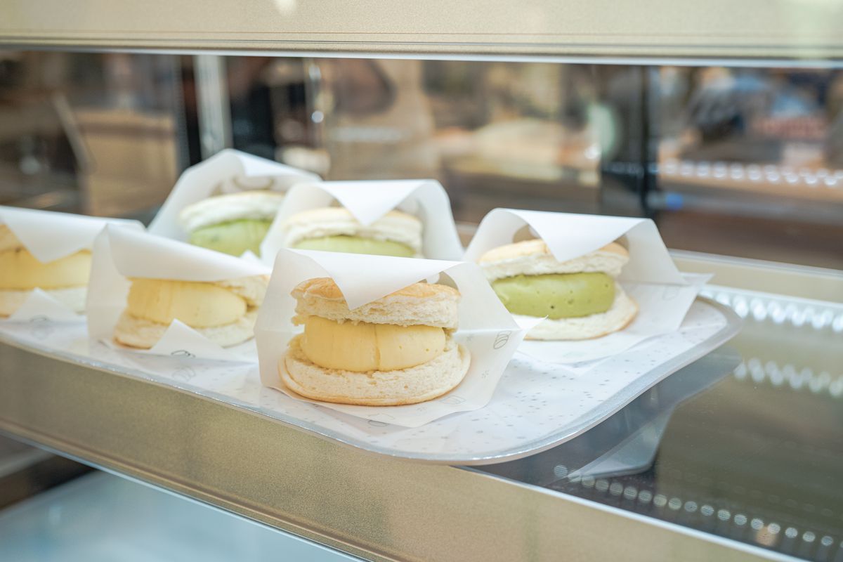 Pancakes filled with cream and green cream sit in a display case.