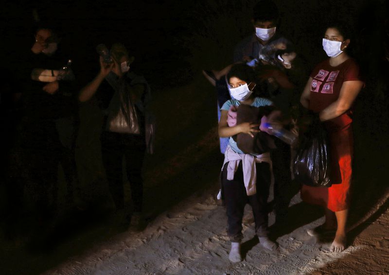 A group of undocumented migrants from Guatemala and and El Salvador seeking asylum are detained near the border wall in McAllen, Texas, on Tuesday, June 22, 2021.