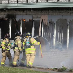 Salt Lake City fire crews pull down plywood from the windows of a building as they respond to a fire at an abandoned building at 1500 S. Main on Wednesday, Nov. 18, 2015. The building is considered a total loss. 