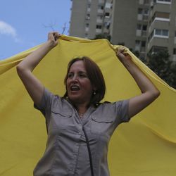 An anti-government demonstrator waves a large Venezuelan flag during a protest against the government of Venezuela's President Nicolas Maduro in Caracas, Venezuela, Sunday, Aug. 6, 2017. Months of protests are fueled by widespread anger over food shortages, triple-digit inflation and high crime.