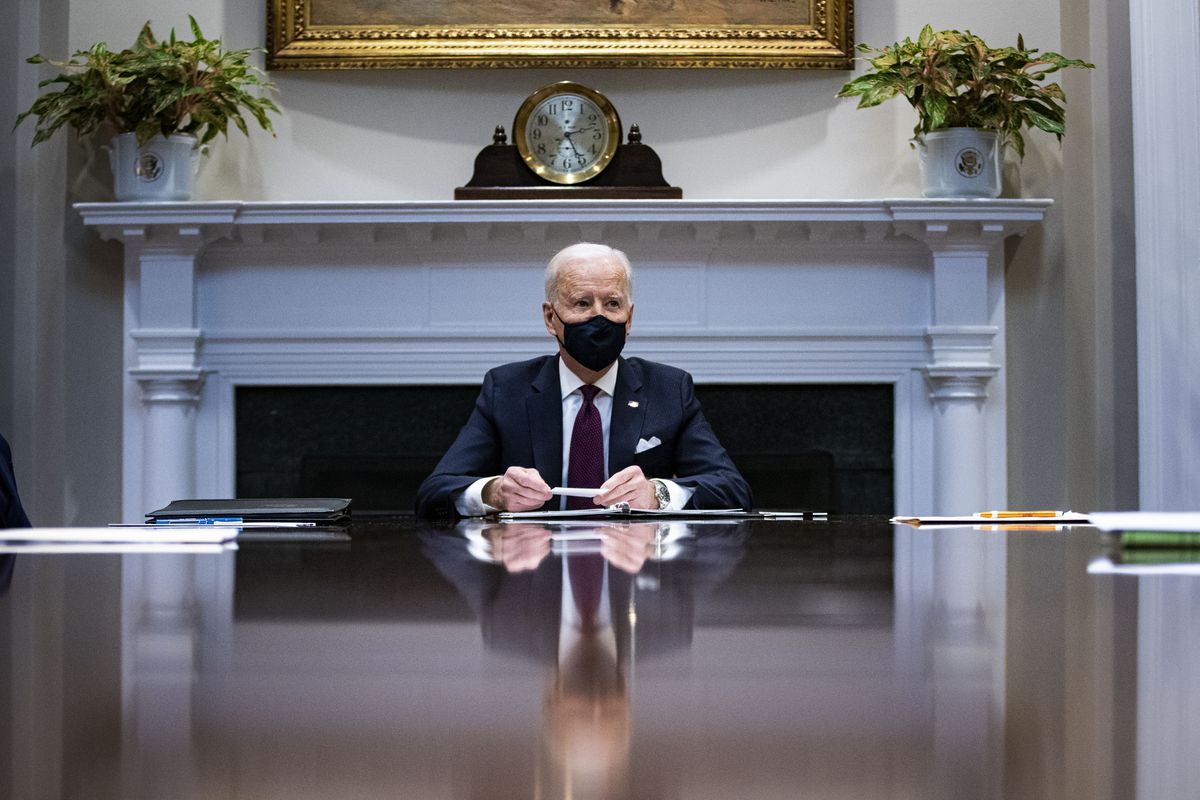 President Biden sitting at a large table alone.