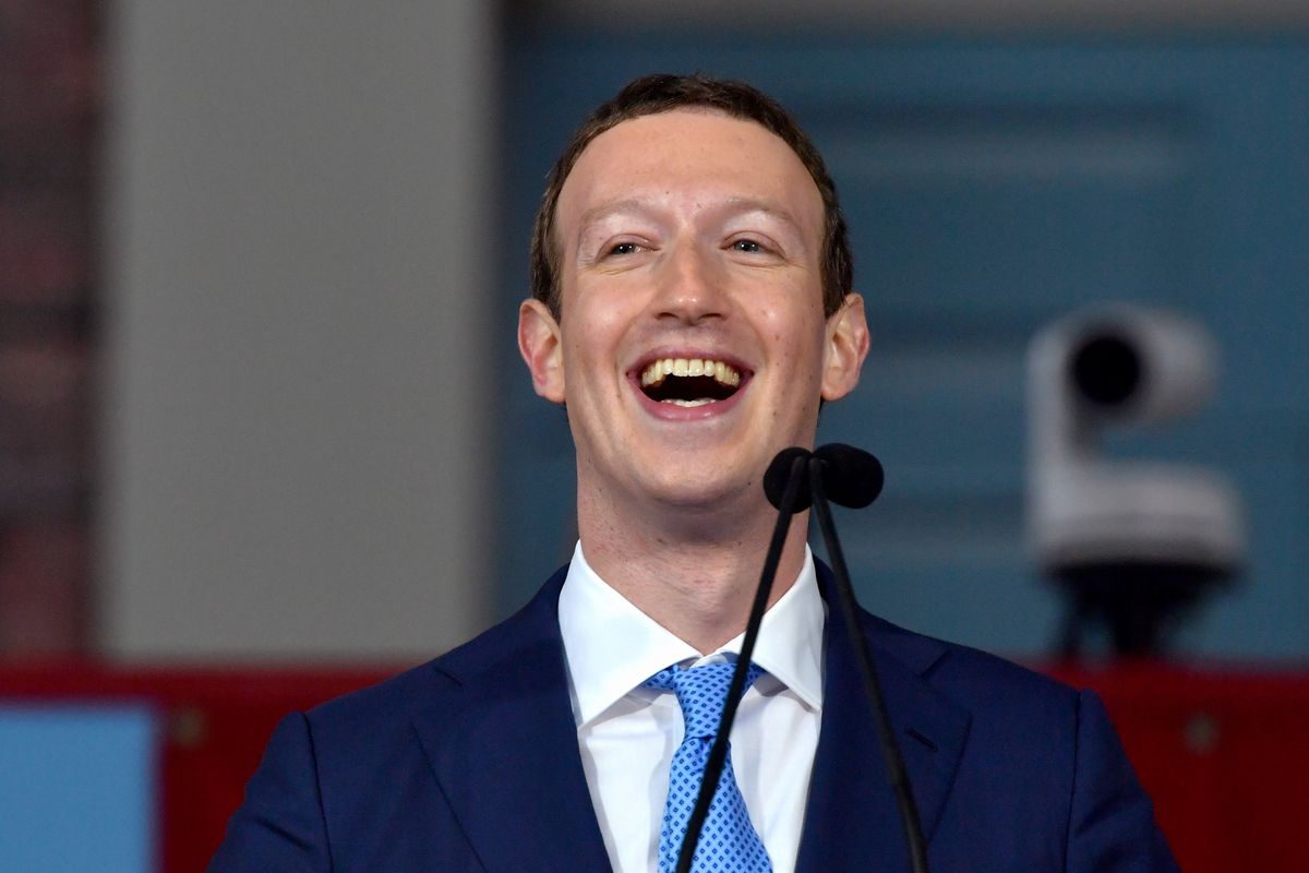 Facebook founder Mark Zuckerberg in a suit and tie laughs onstage at Harvard Commencement.