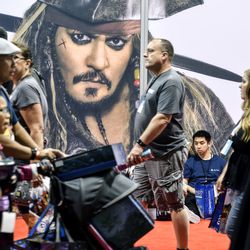 Visitors walk past a picture of Disney character Captain Jack Sparrow during the D23 Expo at the Anaheim Convention Center in Anaheim, Calif., on Friday, July 14, 2017.