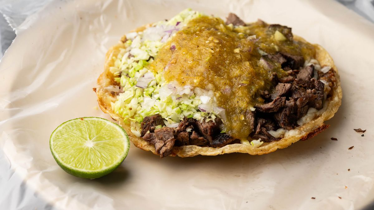 A grilled beef taco with a slice of lime.
