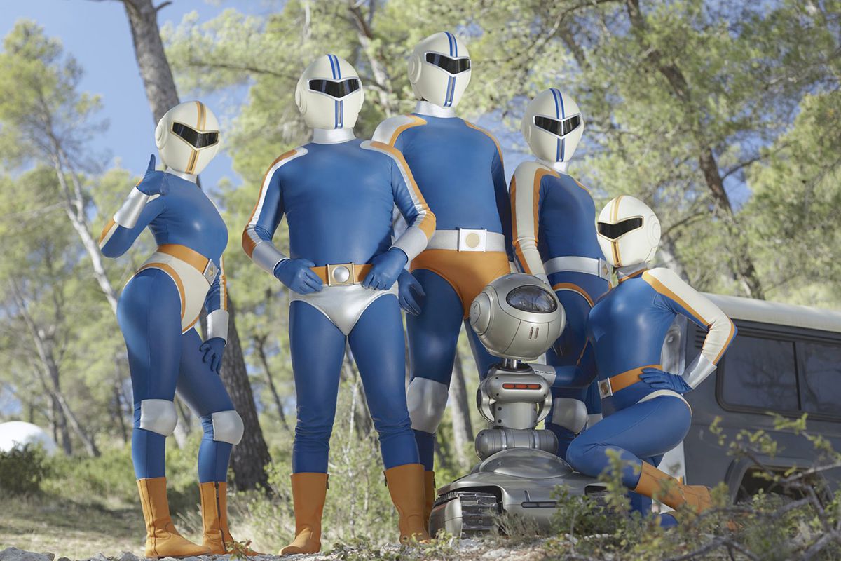 The five superheroes of Tobacco Force and their robot sidekick pose on a wooded hill in a still from Smoking Causes Coughing