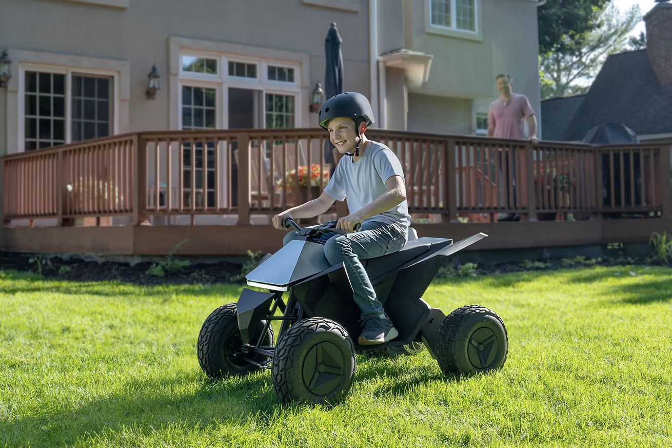 A child riding on a Cyberquad for Kids in a grassy garden.