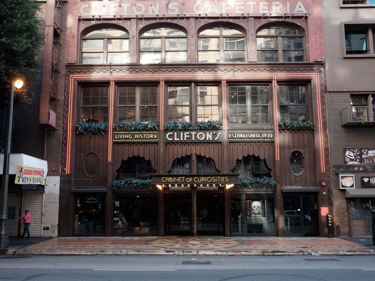 The exterior of Clifton’s Cafeteria in Los Angeles. The facade is brown and red and there is a sign that reads: living history, Clifton’s, established 1932, cabinet of curiosities.