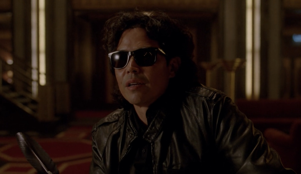 a dark haired man in a leather jacket with sunglasses