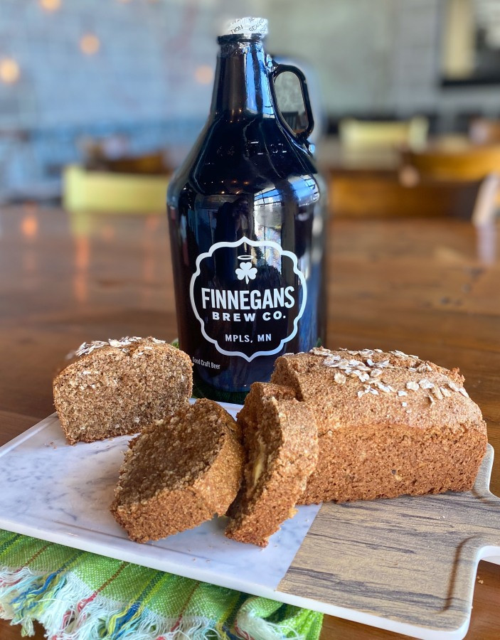 A loaf of Irish soda bread in front of a Finnegans Brew Co. growler