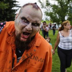 Kevin Williams growls and hobbles his way into Sugarhouse Park after the 10th annual Zombie Walk in Salt Lake City on Sunday, Aug. 6, 2017.
