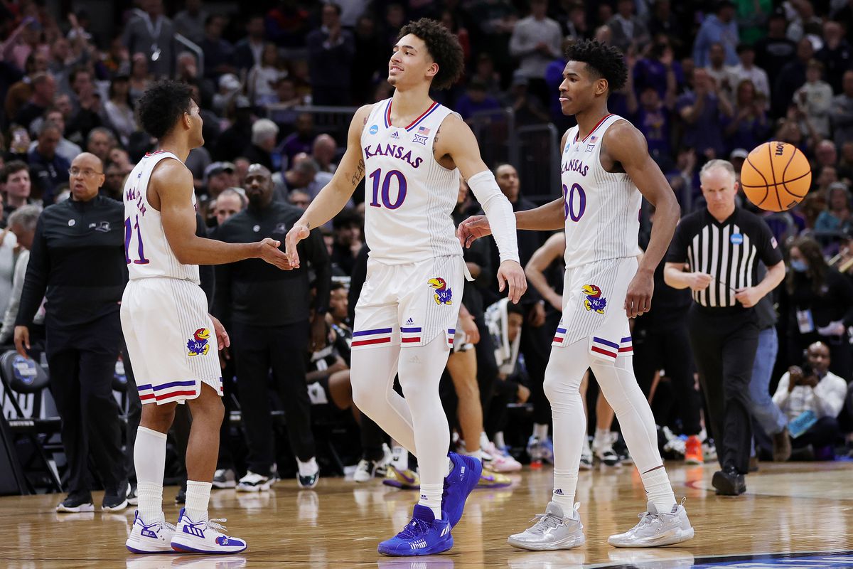Remy Martin, Jalen Wilson and Ochai Agbaji of the Kansas Jayhawks celebrate after the 66-61 win over the Providence Friars in the Sweet Sixteen round game of the 2022 NCAA Men’s Basketball Tournament at United Center on March 25, 2022 in Chicago, Illinois.
