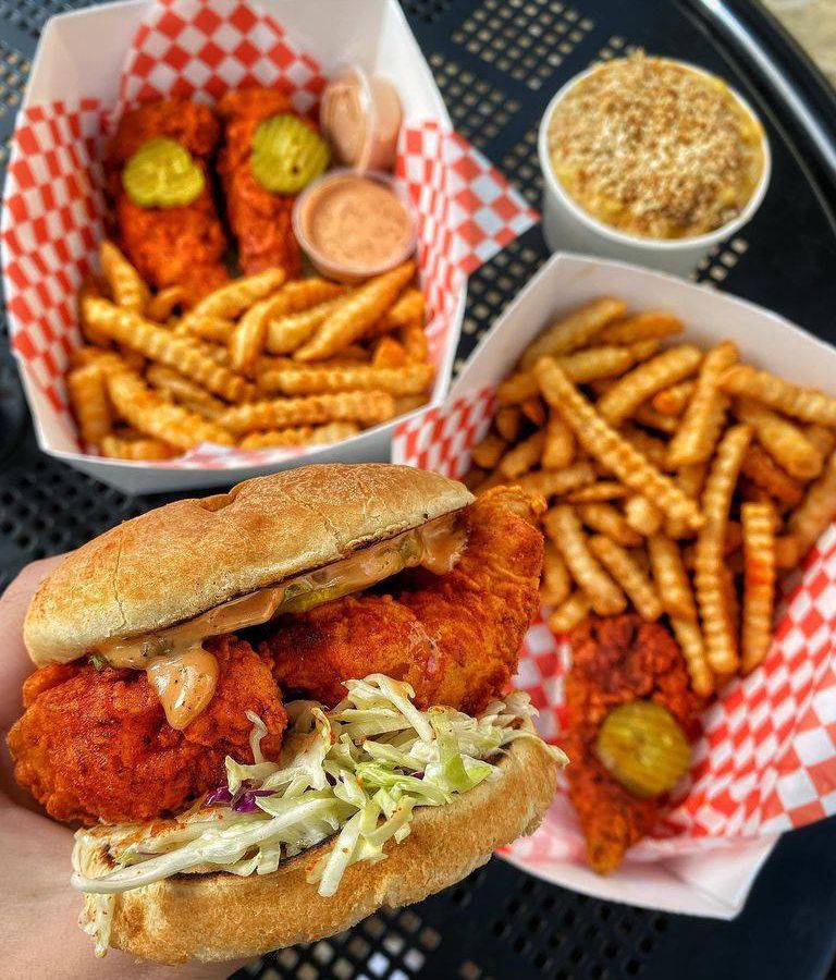Baskets of crinkle-cut fries and spicy chicken sandwiches atop red-and-white checkered paper