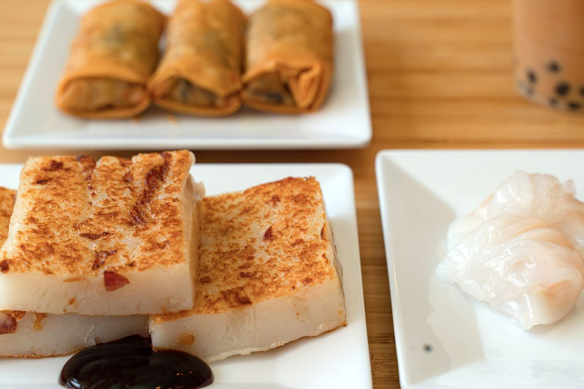 Daikon cakes, crispy spring rolls, har gow and boba tea sit on a table. 