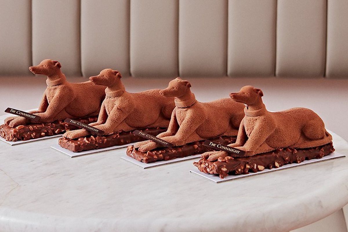 Four chocolate patisserie dogs sitting in a row on a marble effect tabletop