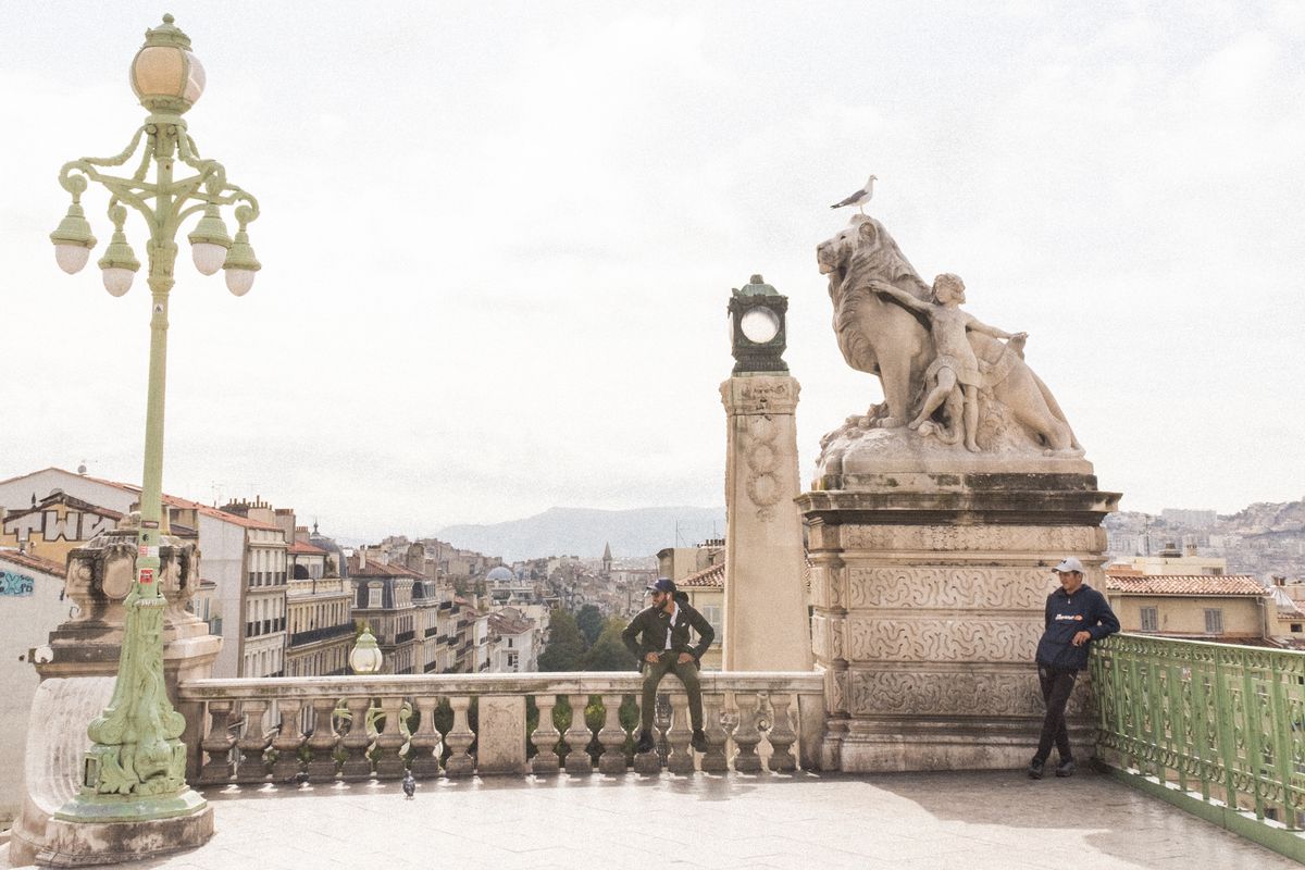 A man sits on a railing over Marseilles, France