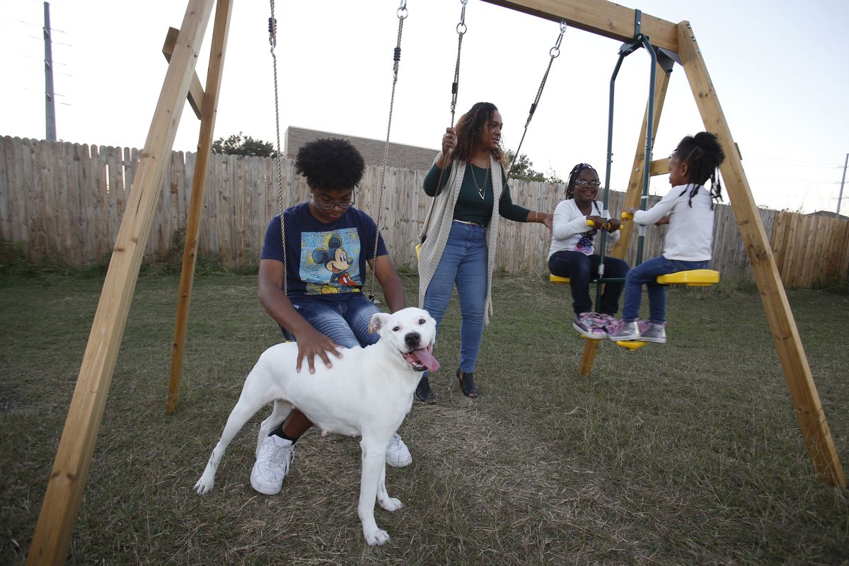 Rosalia Tejeda, second from left, plays with her children, from left, son Juscianni Blackeller, 13; Adaliana Gray, 5, and Audrey Gray, 2, in their backyard in Arlington, Texas, Monday, Oct. 25, 2021. As Tejeda, 38, has learned more about health risks posed by fracking for natural gas, she has become a vocal opponent of a plan to add more natural gas wells at a site near her home. (AP Photo/Martha Irvine) ORG XMIT: RPMI201