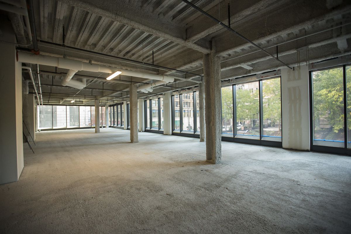 A vast empty room with floor to ceiling windows and supporting beams.