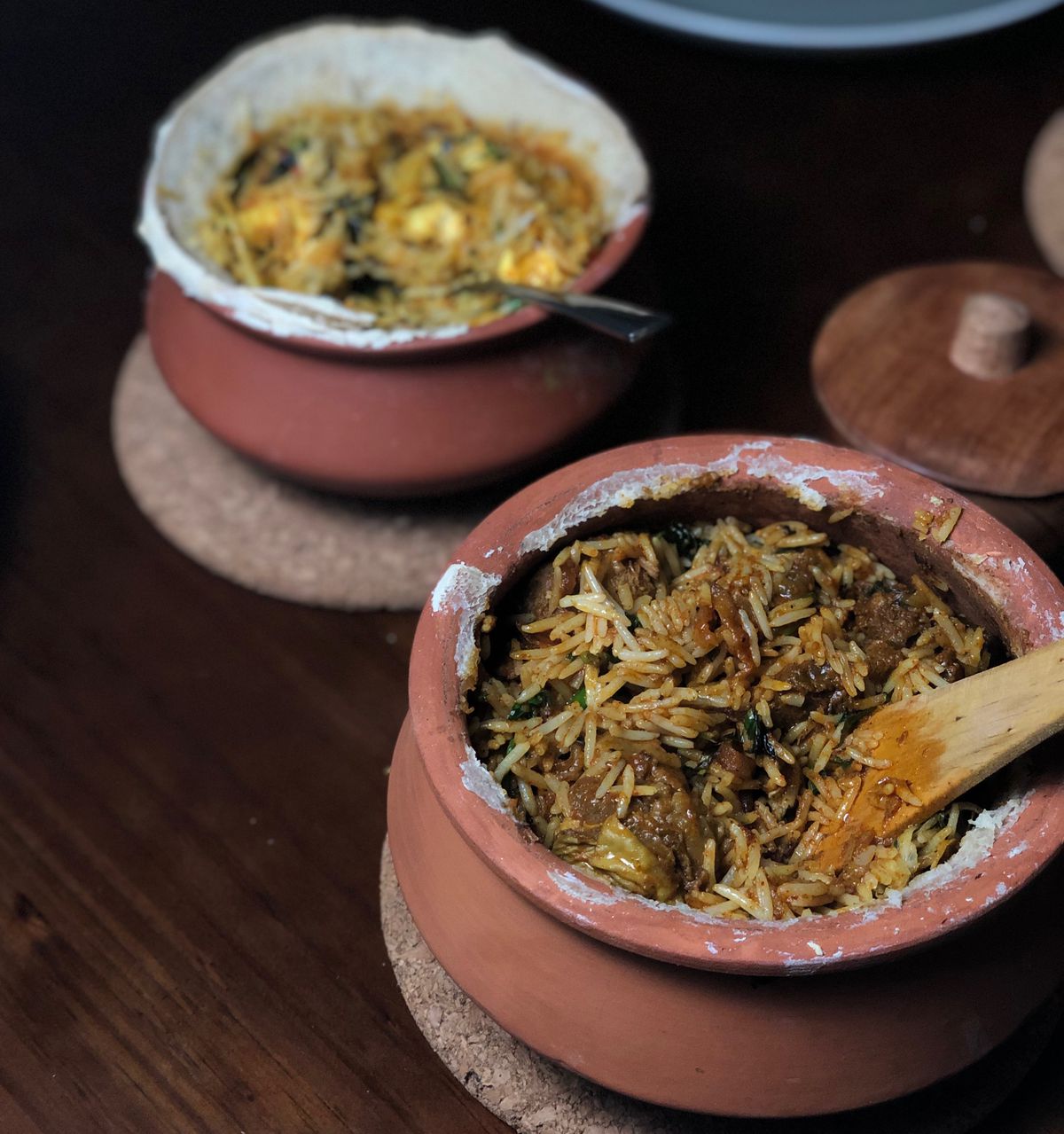 Two brown earthenware vessels full of the indian rice dish biryani