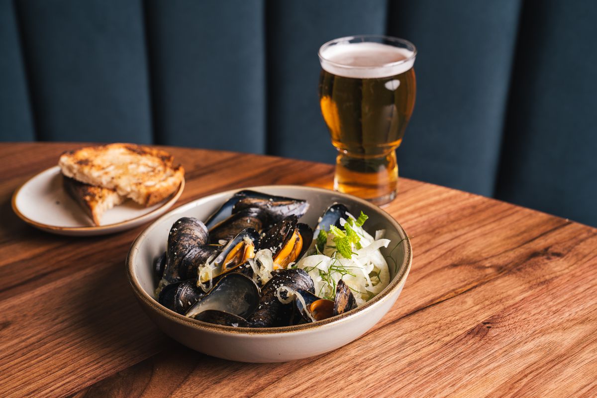 A table laid with a bowl of mussels and a glass of beer.