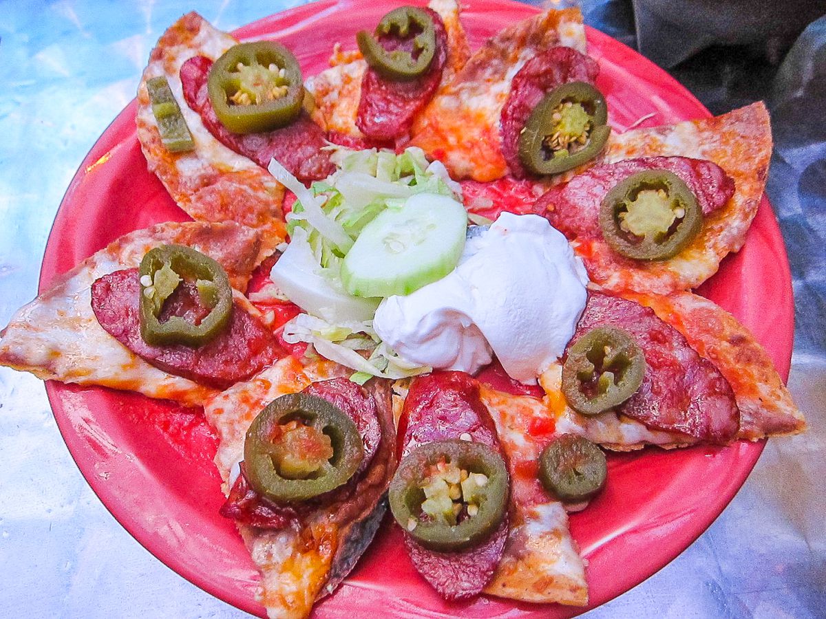 Nachos topped with jalapeno, sour cream, and lettuce are arranged in a starburst pattern.