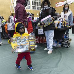 A young child walks with a new toy during a toy giveaway, Sunday, Dec. 19, 2021, at Kennedy–King College in Englewood. | Anthony Vazquez/Sun-Times