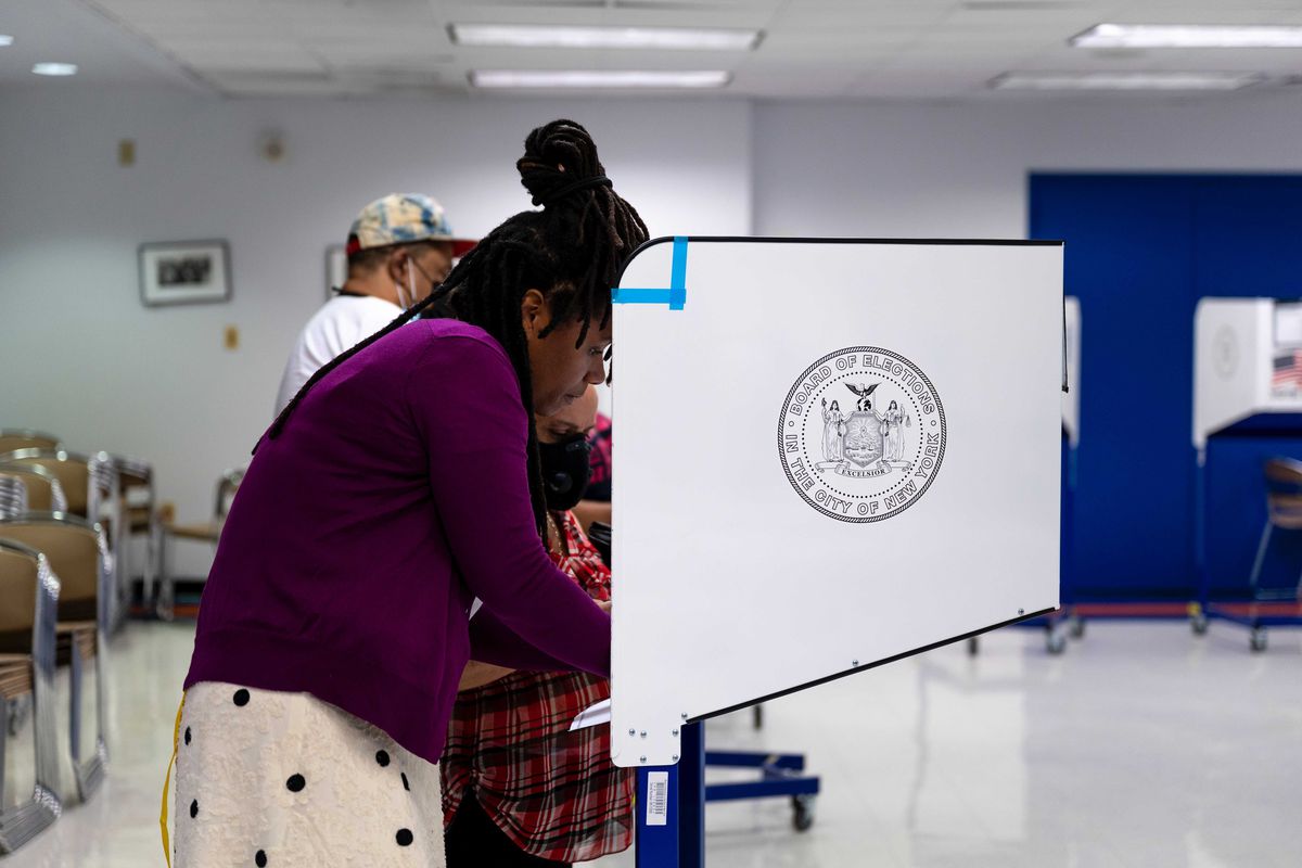 A voting site worker helps a Spanish-speaking elderly woman fill out her ballot at Hostos Community College in The Bronx, June 22, 2021.